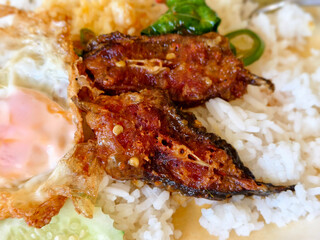Thai spicy stir-fried crispy catfish with rice, fried egg, and basil on plate
