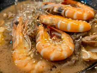 Shrimp simmering in creamy broth with sesame seeds and meat slices