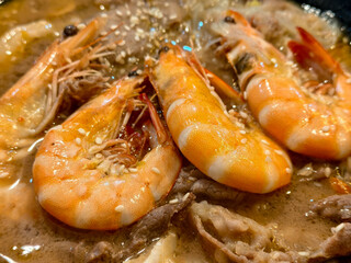 Shrimp simmering in creamy broth with meat slices and sesame seeds
