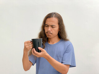 long-haired man holding and looking at a cup