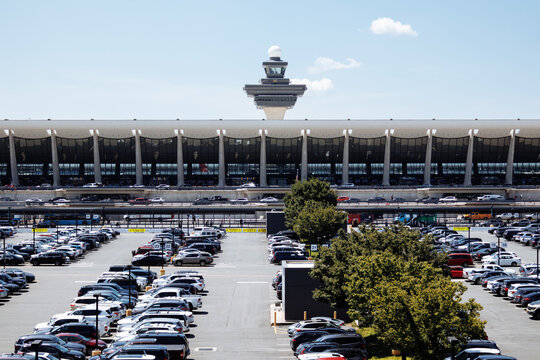 View of Washington Dulles airport terminal and parking lot under clear sky on a sunny day. g.