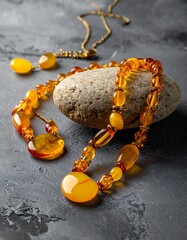 Close-up of amber jewelry set on a rough stone with a matching necklace and earrings on a textured, gray surface