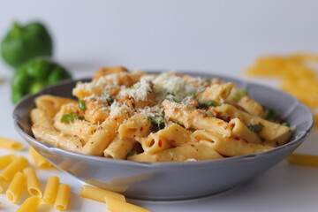 Creamy rigatoni in white sauce topped with grated cheese, herbs, and red pepper flakes