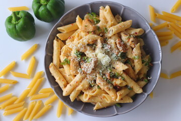 Creamy rigatoni in white sauce topped with grated cheese, herbs, and red pepper flakes