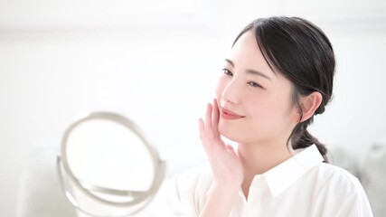 鏡を見る肌のスキンケアを確認する美人な黒髪のショートカットの女性　美容やビューティー、美肌のイメージの動画