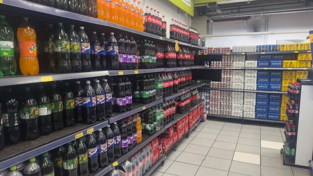 BELO HORIZONTE, MG/BRAZIL - November 16 2025: Supermarket aisle stocked with shelves full of various soft drink and beer brands, including Coca-Cola, Fanta, Sprite, Guaranapan, Kuat