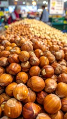 Close-up shows a pile of shiny brown hazelnuts at a grocery store with blurred shoppers