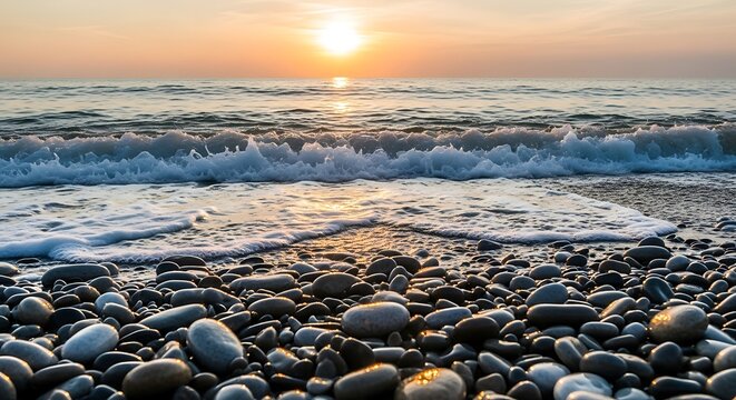 Golden sunset over a pebble beach with gentle waves washing over smooth stones