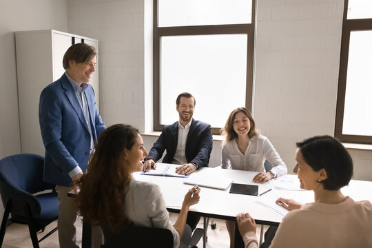 Confident senior male leader guide conversation with diverse coworkers team