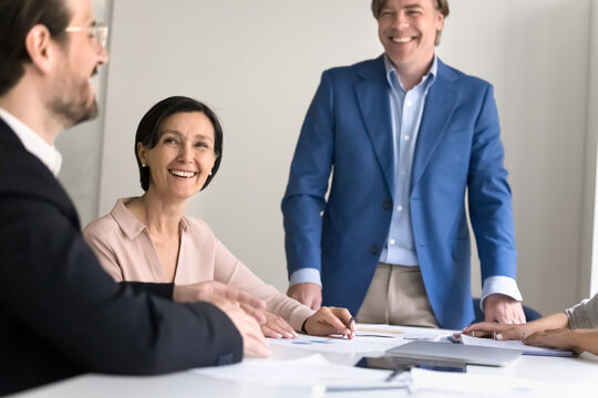 Joyful mature male leader engaged in conversation with diverse colleagues