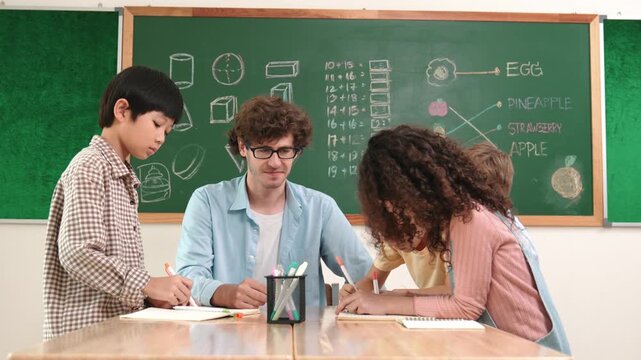 Smart teacher explain idea while diverse children drawing mind map while group of diverse student working together to do class work. Attractive instructor teaching and talking about working. Pedagogy.