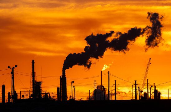 oil refinery petrochemical plant oil gas and energy production with flare stack smoke pollution emission, chemical and polymer production engineering technology for climate change at sunset time