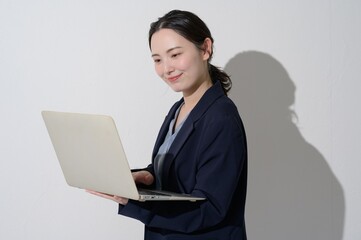 A Japanese woman holding a computer on a white background