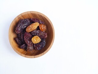 Dried raisins placed in a wooden cup  placed on a white background. Healthy fruit.