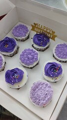 A dozen of cupcake with birthday decoration white and purple colour.