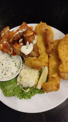 A close up picture off fish and chips with mayonnaise sauce and salad