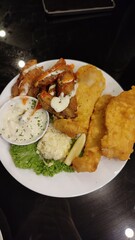 A close up picture off fish and chips with mayonnaise sauce and salad