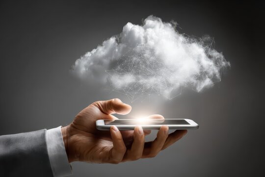 Businessman interacts with smartphone and cloud technology while using a laptop in a modern office environment