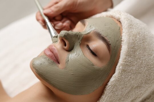 Applying a clay mask to the face for skincare at a spa during a relaxing self-care session