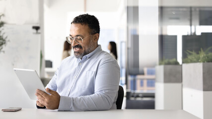 Happy mature Indian business professional man using financial application