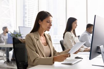 Positive young open office employee woman reading paper document