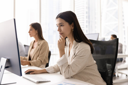 Focused pensive young business professional woman working at pc monitor