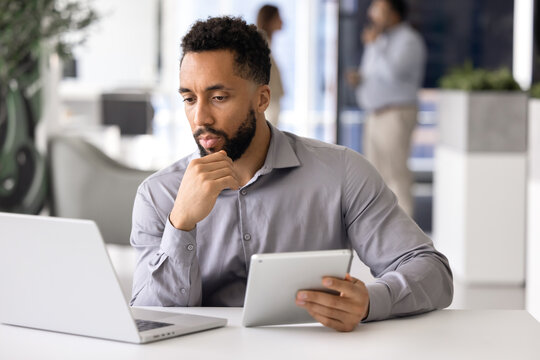Pensive male African professional analyzing online content - Powered by Adobe