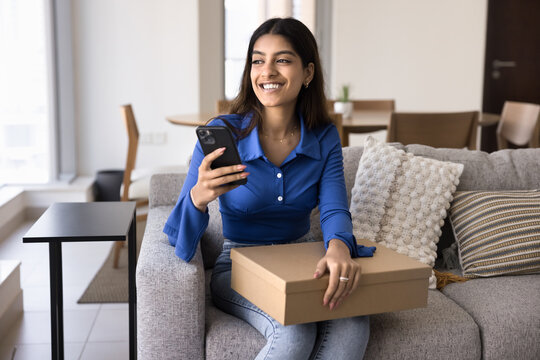 Cheerful young Indian customer woman holding received parcel