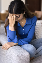 Depressed unhappy young Indian woman touching forehead