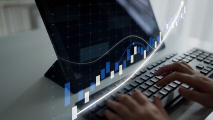 Focused hands typing on a keyboard while analyzing a digital stock market chart displayed on a computer screen, representing financial growth and modern business analysis. Copula
