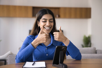 Cheerful Indian woman showing double thumbs up at mobile phone