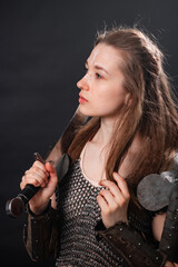 Naklejka premium Portrait of a young woman, fantasy warrior in armor with a sword in her hands isolated on a dark background