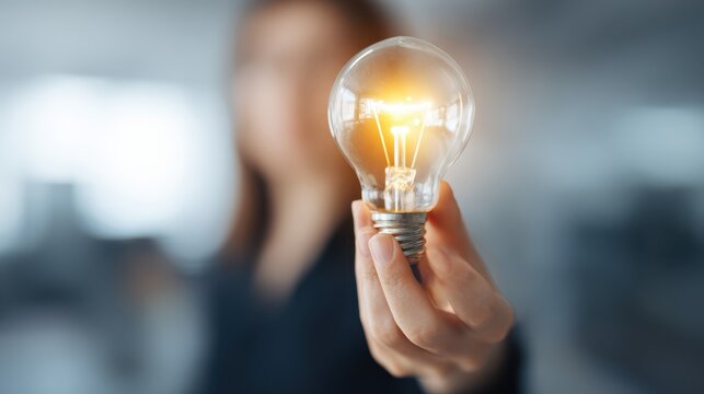 Creative modern office workspace featuring a blurred light bulb design concept held by an individual during a brainstorming session