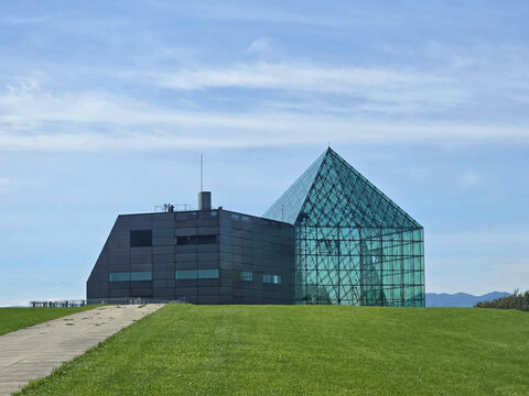 Modern architectural building with glass facade and geometric design under a blue sky - Powered by Adobe