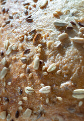 Close-up of Organic Seeded Sourdough loaf, characterized by its use of organic ingredients and a mix of various seeds, including pumpkin, sunflower, sesame and linseed, resting on a wooden cutting