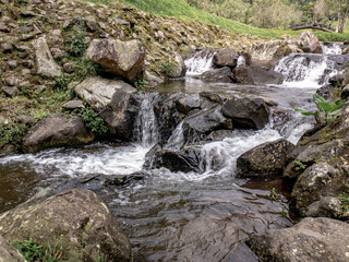 Smooth water flow over natural rocks in an Indonesian highland garden, perfect for calm nature concepts, eco visuals, and travel projects