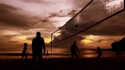 Young people playing beach volleyball by the ocean at sunset - Powered by Adobe