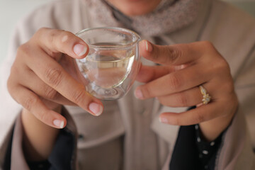 Holding a small glass of clear liquid in a cozy setting