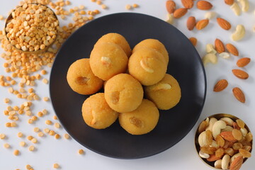 Chana dal motichur laddus stacked on a black plate, garnished with dry fruits