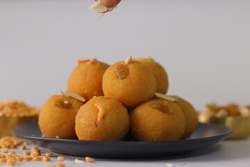 Chana dal motichur laddus stacked on a black plate, garnished with dry fruits