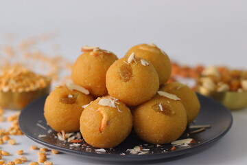 Chana dal motichur laddus stacked on a black plate, garnished with dry fruits