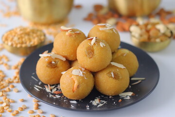 Chana dal motichur laddus stacked on a black plate, garnished with dry fruits