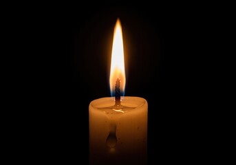 Warm glowing flame of a single white candle burning brightly in the dark.