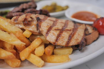 Grilled chicken served with fries and sides for a tasty meal