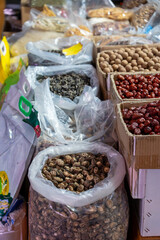 Vertical shot of a market stall display with clear plastic bags and cardboard boxes full of various dried goods including shiitake mushrooms red dates and longan fruit