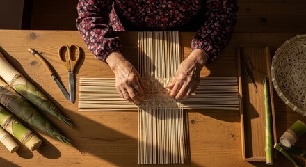 Elderly hands weaving traditional bamboo basket using natural reed strips on wooden workshop table with crafting tools