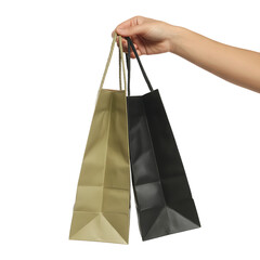 Human hand holding two different colored paper shopping bags one brown and one black isolated on transparent background