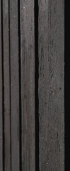 Close-up of dark wooden planks with a textured surface. The wood shows natural grain patterns and variations in color, creating a rustic appearance.