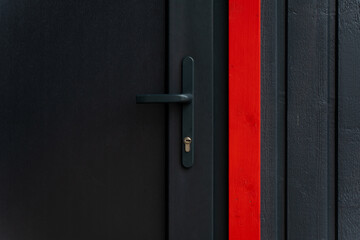 Architectural doorway detail with elongated grip handle integrated into textured wall panel beside red accent board, giving contrast and practical fastening layout