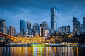 The illuminated modern city skyline and waterfront with light reflections on the river at night in...